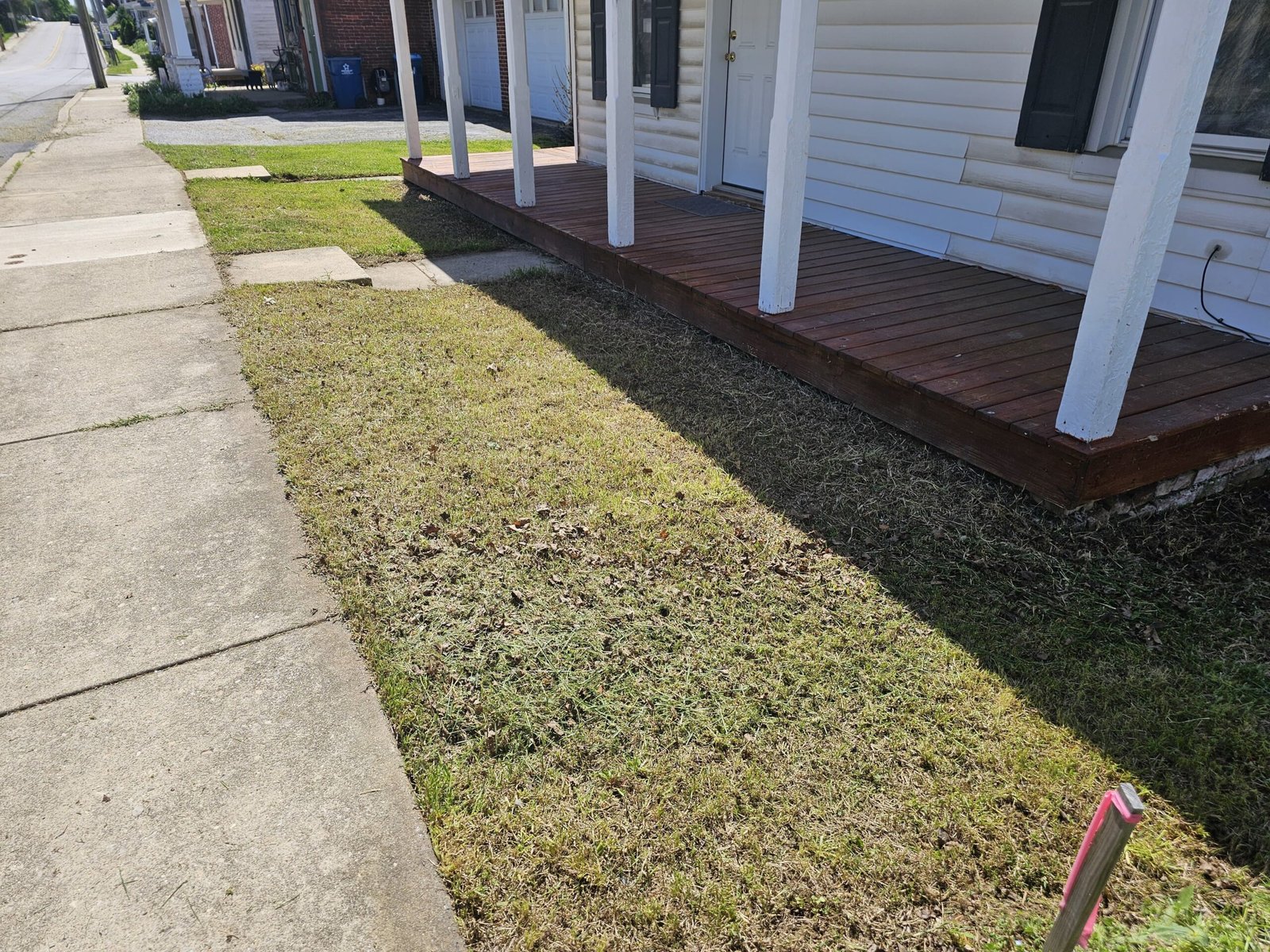 Small front yard lawn next to a porch and sidewalk in a residential neighborhood
