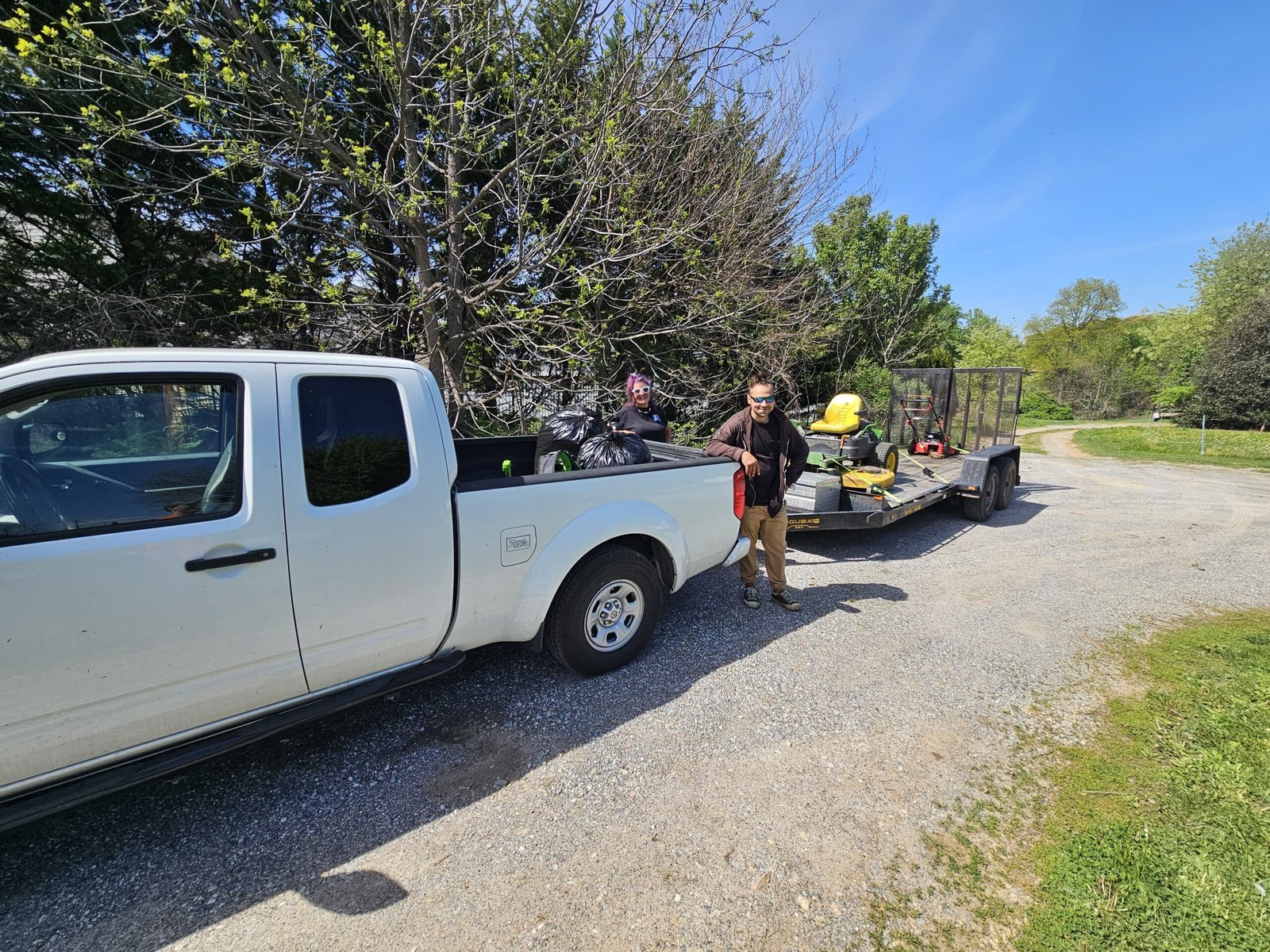 Crew with a pickup truck and trailer loaded with lawn cleanup equipment and yard debris bags